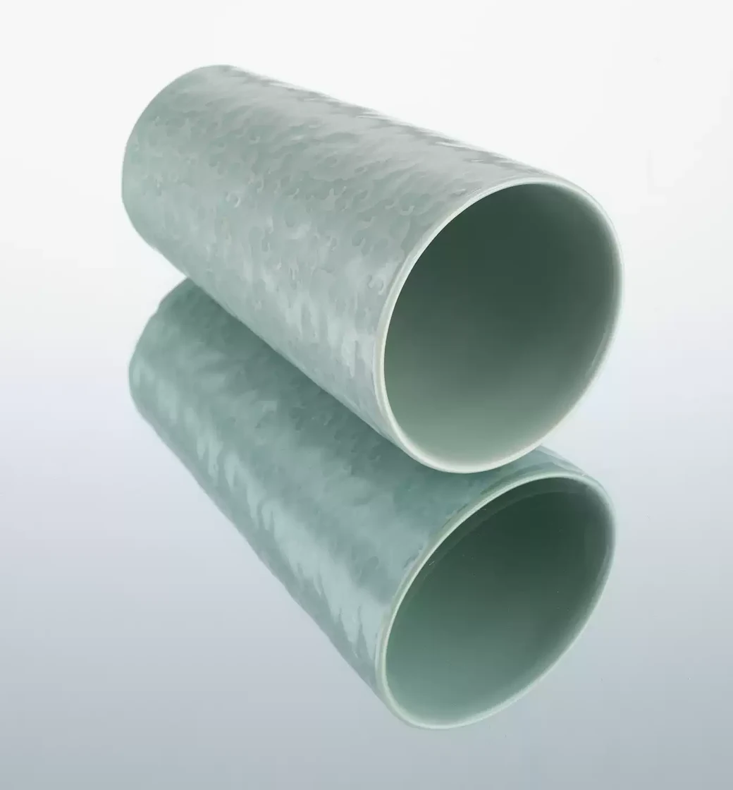 The Wave Cup resting on its side, reflected in a pale studio surface